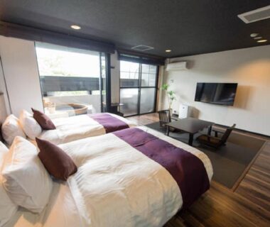 Three twin beds with balcony, low table seating and wall-mounted TV at LiVEMAX RESORT Aki Miyahama Onsen, Hiroshima