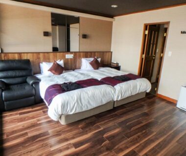 Twin beds on wooden floor with recliner in LiVEMAX RESORT Aki Miyahama Onsen, Hiroshima