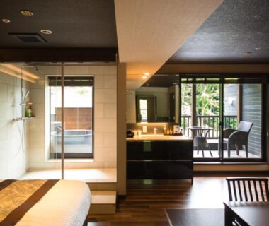 Glass-walled bathing area, vanity and balcony seating in wood-floored room at LiVEMAX RESORT Aki Miyajima Hiroshima