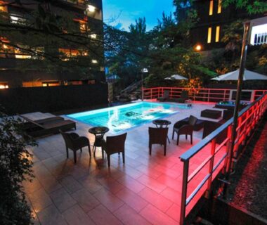 Evening lit outdoor pool deck with lounge chairs and red railing at LiVEMAX RESORT Aki Miyajima, Hiroshima