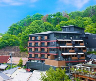 Multi-story ryokan with wooden balconies against a forested hillside in Miyajima, Hiroshima
