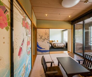 Tatami room with low table, fusuma artwork and bed at LiVEMAX RESORT Kaga Yamashiro, Ishikawa