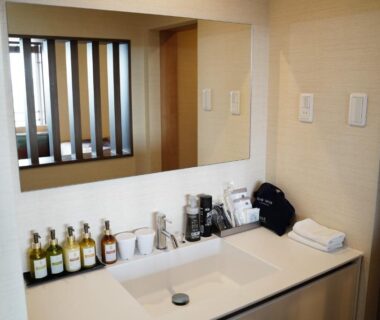 Clean sink vanity with bottled toiletries, mirror and hand towel in guest bathroom at LiVEMAX RESORT Kaga Yamashiro, Ishikawa