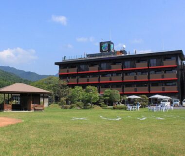 Grassy lawn with gazebo and outdoor seating in front of LiVEMAX RESORT Kinugawa, mountain backdrop, Tochigi