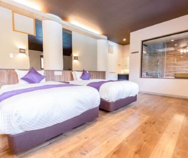 Two single beds with wooden flooring and glass-partitioned bath at LiVEMAX RESORT Kusatsu Onsen in Gunma Kantō Japan
