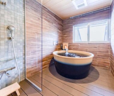 Round wooden soaking tub and shower in a tiled bathing room at LiVEMAX RESORT Kusatsu Onsen, Gunma, Kantō, Japan