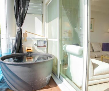 Round soaking tub on balcony beside sliding glass doors to lounge at LiVEMAX RESORT Setouchi, Hyōgo