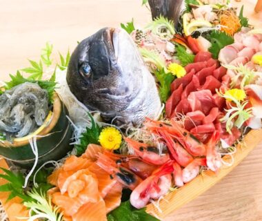 Sashimi assortment on wooden boat platter with fish head and garnishes at LiVEMAX RESORT Shizuoka Amagiyugashima