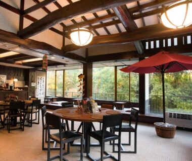 Dining area with wooden beams, round tables and red umbrella at LiVEMAX RESORT Shizuoka Amagiyugashima, Chūbu, Shizuoka