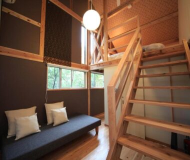 Wooden loft interior with staircase, bench seating and pendant light at Lodge Toranoyu in Ōita
