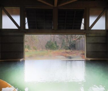 Indoor onsen bath framed by wooden walls at Lodge Toranoyu in Ōita, Kyūshū