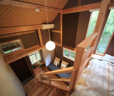 Loft bedroom with wooden staircase and sitting area at Lodge Toranoyu in Ōita, Kyūshū