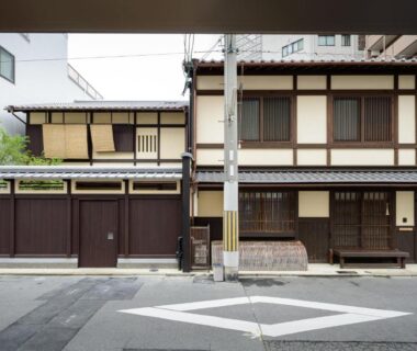 Two-story wooden ryokan facade with shoji windows, noren curtain and street entrance in Kyoto, Kansai, Japan