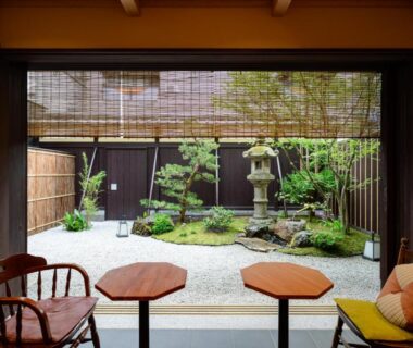 Seating and low tables with bamboo blinds overlooking courtyard garden and stone lantern at Luck You Kyoto, Kansai Japan