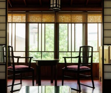 Traditional shoji seating area with wooden chairs and low table overlooking garden at Machi no Odoriba, Ishikawa