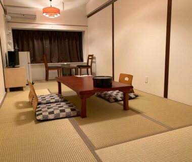 Traditional tatami room with low wooden table, floor cushions, TV and desk near window