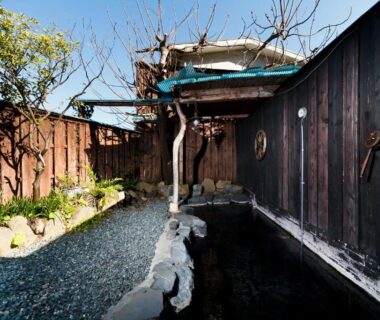 Outdoor onsen bath with stone path and wooden fence at Manten-no-Hoshi, Kanagawa