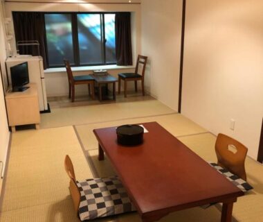 Traditional tatami room with low wooden table, floor cushions, sliding doors and window seating at Manten-no-Hoshi, Kanagawa