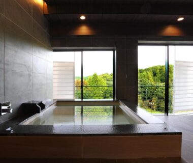 Indoor wooden soaking tub with garden view through sliding windows at Manten no Tsujinoya, Ishikawa