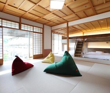 Spacious tatami room with shoji screens, colorful triangular cushions and raised sleeping platform at Manten no Tsujinoya, Ishikawa