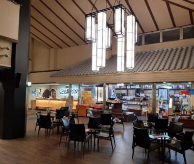 Spacious ryokan lobby with tables, hanging lanterns and a souvenir counter at Manza Onsen Nisshinkan, Gunma