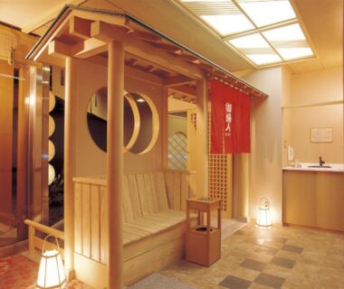 Wooden entrance alcove with red noren, shoji screens, stone floor and lanterns at Maruei in Yamanashi, Chūbu, Japan