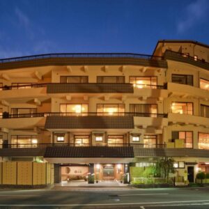 Illuminated multi-story ryokan facade with balconies and street-level entrance at dusk in Yamanashi, Chūbu