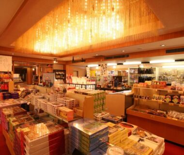 Warm-lit ryokan gift shop with shelves of packaged souvenirs, Maruei, Yamanashi, Chūbu, Japan