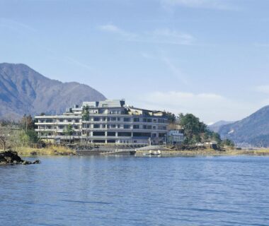 Multi-story lakeside ryokan building with mountain backdrop in Yamanashi, Chūbu region