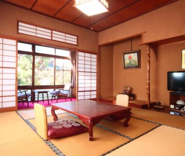 Traditional tatami room with low table, zabuton cushions, shoji screens and garden-facing verandah at Maruka Ryokan, Nagano