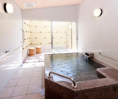 Indoor onsen bath with stone tub and handrail at Marumine Kanko Hotel Fukushima