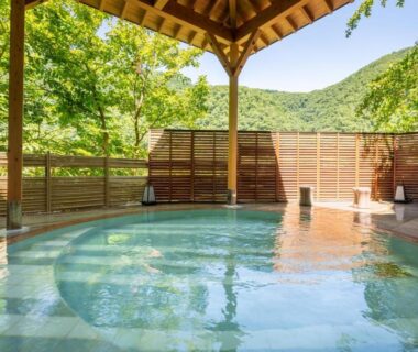 Roofed outdoor onsen bath with wooden decking and mountain views at Marumine Kanko Hotel, Fukushima