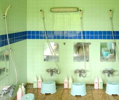 Communal tiled shower area with stools, hand showers, mirrors and toiletries at Maruyaso in Yamanashi, Chūbu