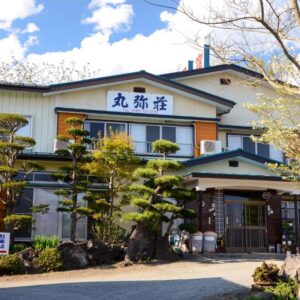 Exterior entrance of Maruyaso with manicured pines and traditional signage in Yamanashi, Chūbu
