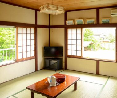 Tatami room with low table, shoji screens and garden-facing windows at Maruyaso in Yamanashi, Chūbu