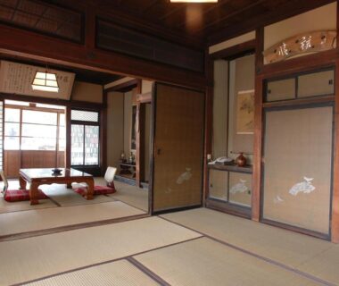 Spacious tatami room with low table, zabuton cushions, shoji screens and sliding fusuma doors at Masuya Ryokan, Nagano