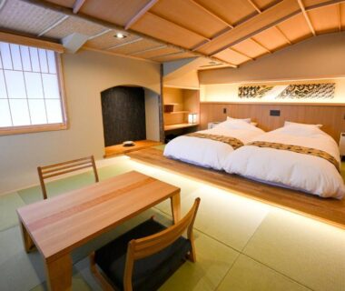 Tatami room with low beds, shoji screens and wooden table at Matsubaya Ryokan in Kyoto