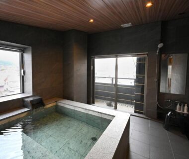 Indoor tiled onsen bath with large windows and balcony access at Matsubaya Ryokan in Kyoto