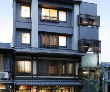 Four-story ryokan facade with wooden lattice windows and main entrance in Kyoto