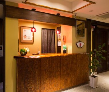 Warm wooden reception counter with noren and lanterns at Matsubaya Ryokan Kyoto