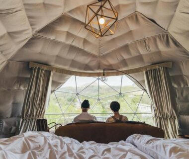 Couple seated inside geodesic dome room with bed and panoramic window at Matsukaneya Annex, Yamagata, Japan