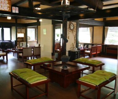 Spacious wooden lounge with low tables and green-cushioned benches at Matsunoi Ryokan, Gifu, Chūbu, Japan