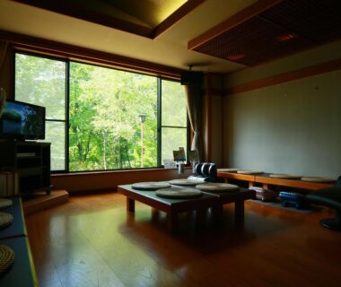 Low table with floor cushions and large window overlooking green trees at Matsunoi, Gifu