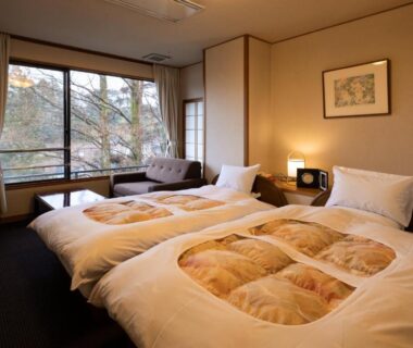 Twin beds with warm comforters and seating by large window at Matsusaki Ryokan, Ishikawa Japan