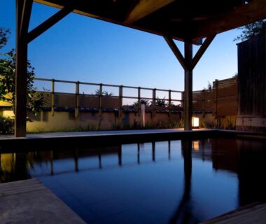 Covered wooden onsen pool at Matsusaki, Chūbu Ishikawa Japan with twilight reflection and lantern-lit veranda