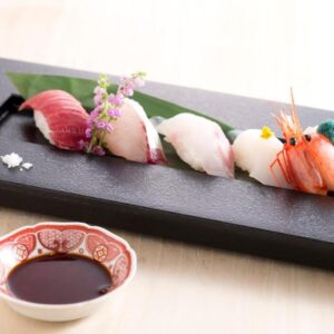 Assorted nigiri sushi on black platter with soy sauce bowl at Matsusaki ryokan in Ishikawa, Chūbu, Japan
