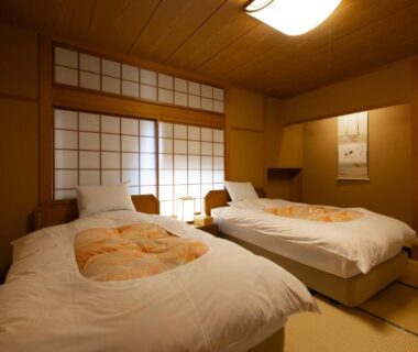 Twin beds on tatami floor with shoji screens, wooden ceiling and hanging scroll in Matsusaki ryokan, Ishikawa