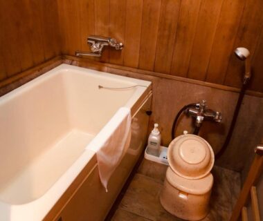 Small deep bathtub with wooden walls, stool, and toiletries at Matsushima Koumura ryokan in Miyagi, Tōhoku