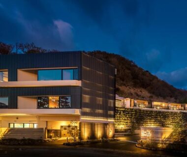 Illuminated multi-level ryokan building on hillside with terraces and warm exterior lighting at dusk in Shizuoka, Chūbu region