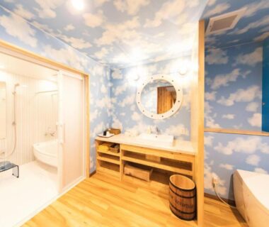 Cloud mural bathroom vanity with round mirror, wooden floor and bathing area at Meijikan, Shizuoka, Chūbu, Japan